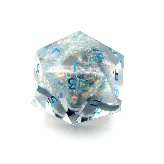 Clear resin D20 chonk showing the 1 face, with a toy penguin inside. The chonk has iridescent mylar tubes and glitter at the bottom, and is inked in ice blue
