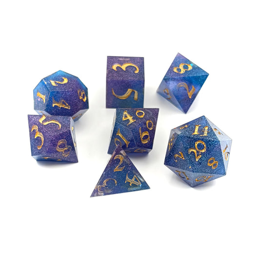 Photo of a set of 7 resin TTRPG dice Rich blue and purple semi-transparent resin with purple glitter. Inked in gold