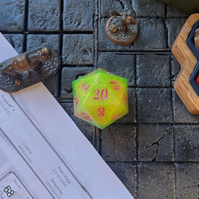 Red & Green D20 chonk with red/pink  and green inking on the numbers shown on a D&D play table