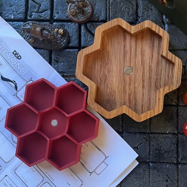 Brick red 3D printed PLA dice tray  with a magnet next to a white oak CNC carved wooden dice tray holder with a magnet on a D&D background 