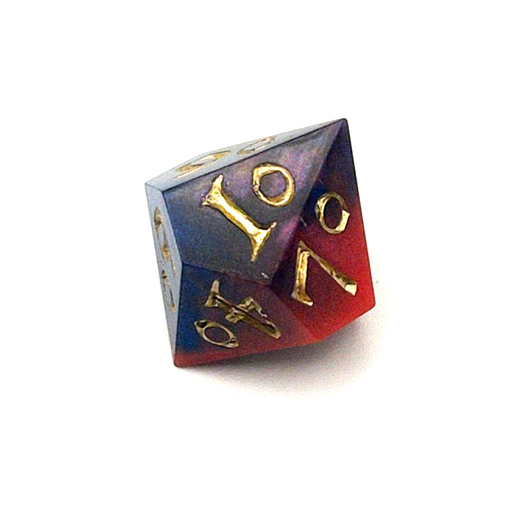 D100 chonk showing the 10 face. The resin is coloured with pigment powders using black, blue and red. The die is inked in chromed gold.