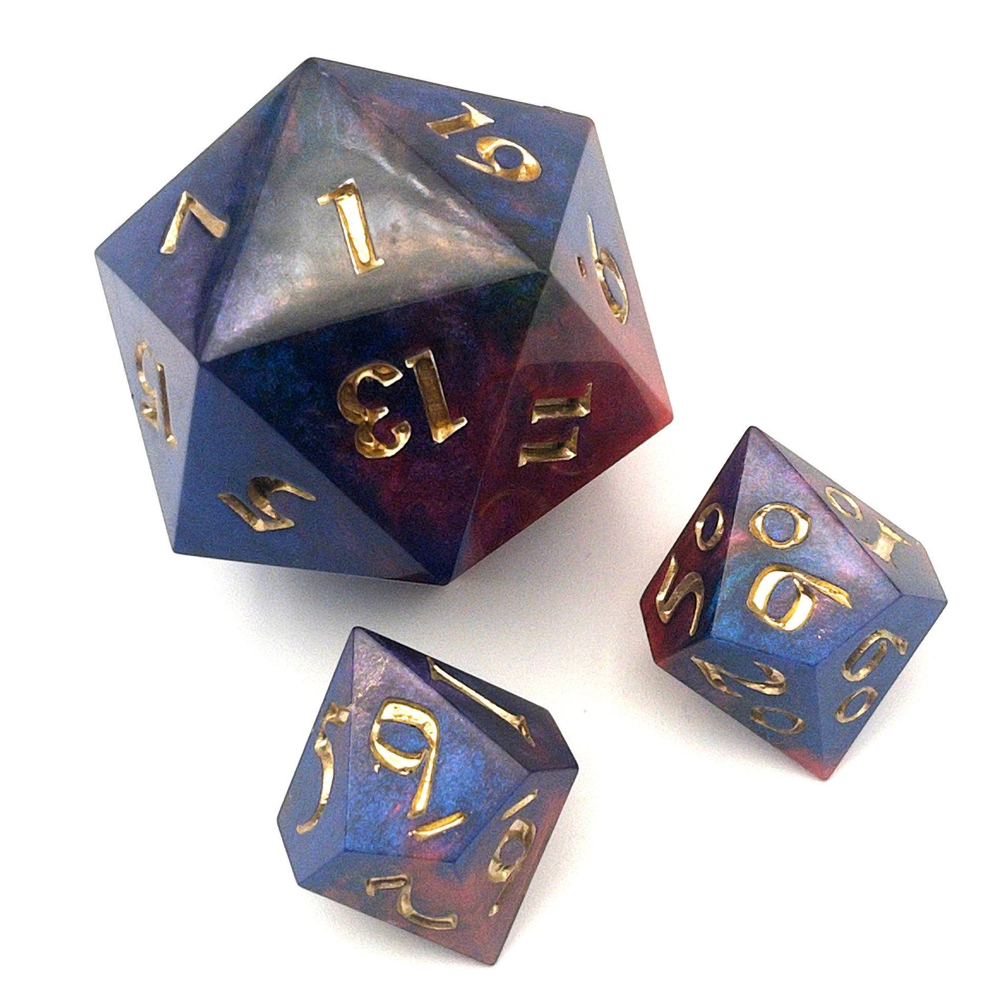 Full set of Mothership dice. The D20 is a chonk, and the D10 and D100 are regular size. The resin is coloured with pigment powders using black, blue and red. The dice are inked in chromed gold.