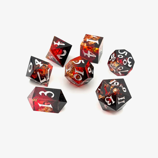 Photo showing 7 resin TTRPG dice. Scarlet resin dye, with gold flakes.
Inking is white