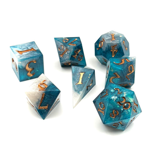 Photo of 7 resin TTRPG dice. Rich teal and white opaque resin, with gold inking