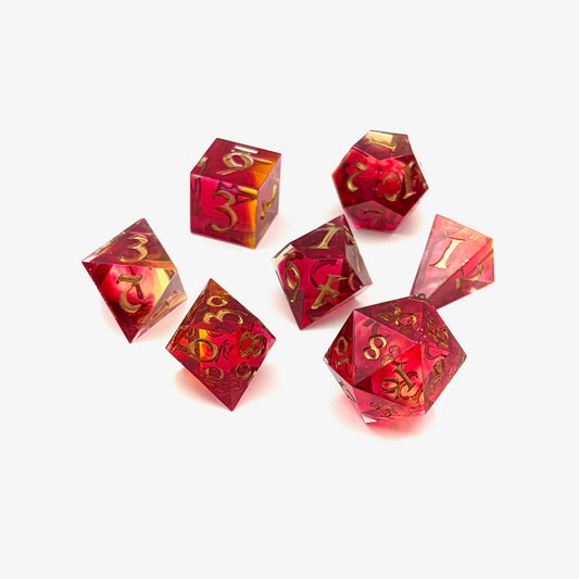 Photo showing 7 resin TTRPG dice. Scarlet and yellow resin dyes.
Inking is gold