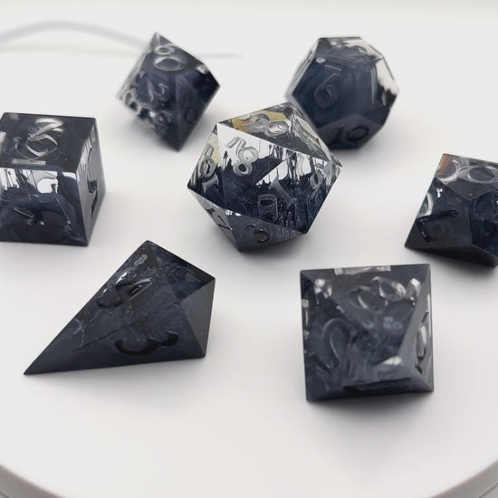 Video showing a full set of clear and black petrie pour style resin dice rotating in a lightbox. Uninked numbers