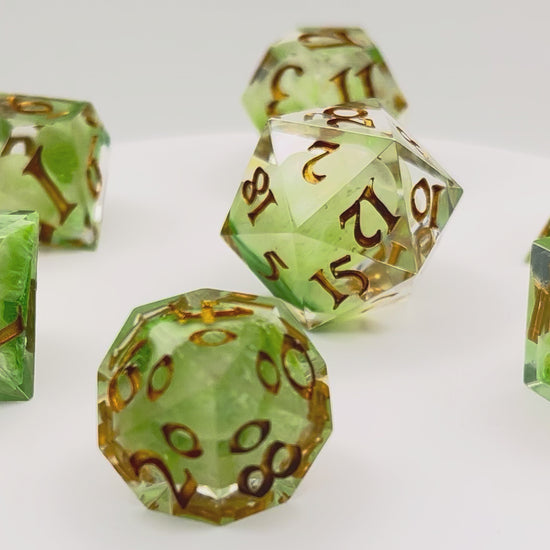 Video showing Full set of TTRPG resin dice, with green and white pigment cast into blanks and then shelled in clear resin and inked in Chromed Gold
