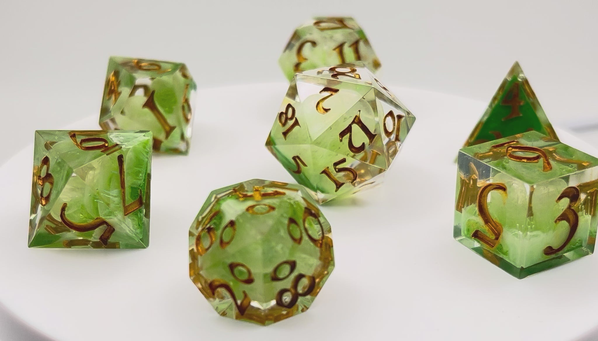 Video showing Full set of TTRPG resin dice, with green and white pigment cast into blanks and then shelled in clear resin and inked in Chromed Gold