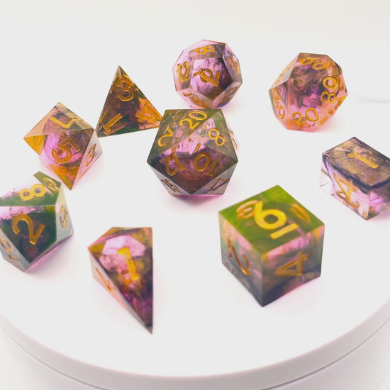 Video of Full set of TTRPG resin dice. Resin is semi-transparent pigmented with gold, black and amber dyes. These are inked in gold