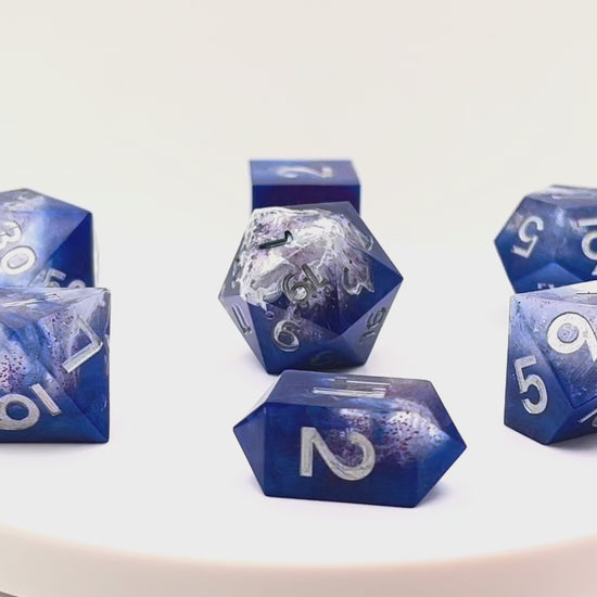 Video showing Full set of TTRPG resin dice, opaque blue in parts, with clear areas with white resin. Inked in silver