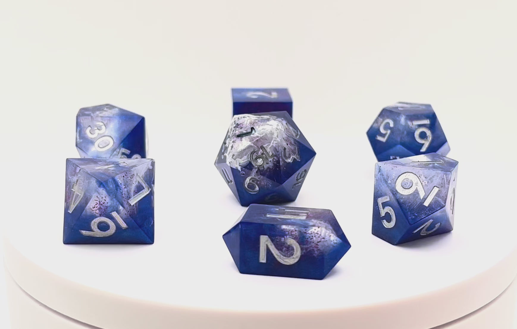 Video showing Full set of TTRPG resin dice, opaque blue in parts, with clear areas with white resin. Inked in silver
