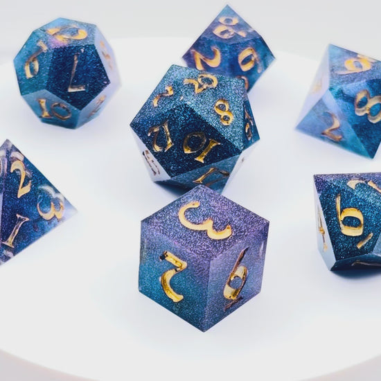 Video showing a set of 7 resin TTRPG dice Rich blue and purple semi-transparent resin with purple glitter. 