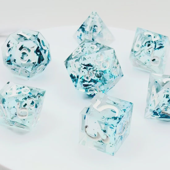 video of a set of 7 TTRPG dice made with clear resin and inked in white paint