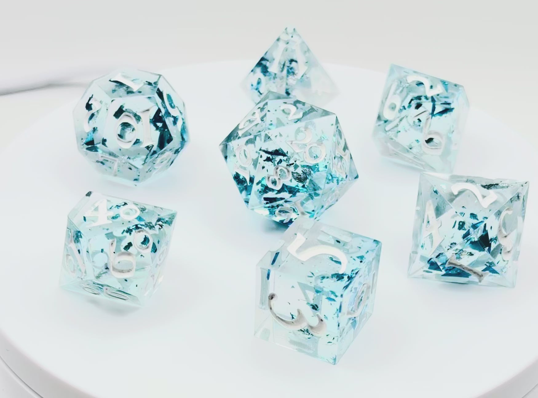 video of a set of 7 TTRPG dice made with clear resin and inked in white paint