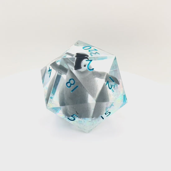 Video showing a clear resin D20 chonk with a toy penguin inside. The chonk has iridescent mylar tubes and glitter at the bottom, and is inked in ice blue
