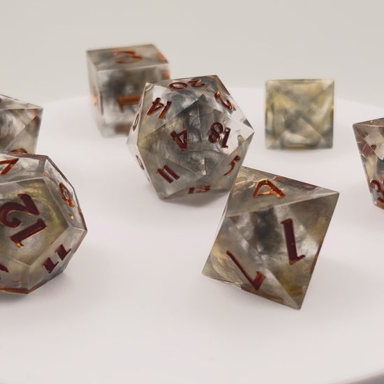 Video showing Full set of TTRPG resin dice using transparent black and gold dyes, inked in metallic copper paint