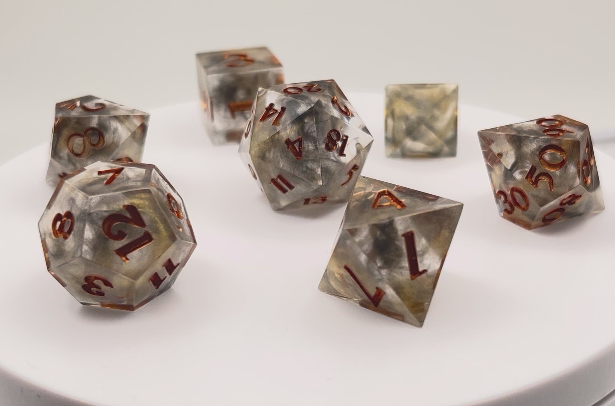 Video showing Full set of TTRPG resin dice using transparent black and gold dyes, inked in metallic copper paint