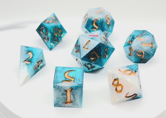 Video of 7 resin TTRPG dice. Rich teal and white opaque resin, with gold inking