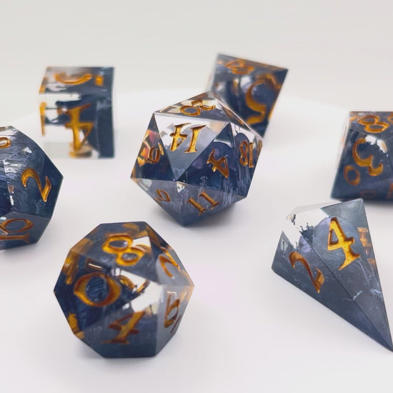 Video showing TTRPG D&D clear with black Petri effect resin dice set inked in gold
