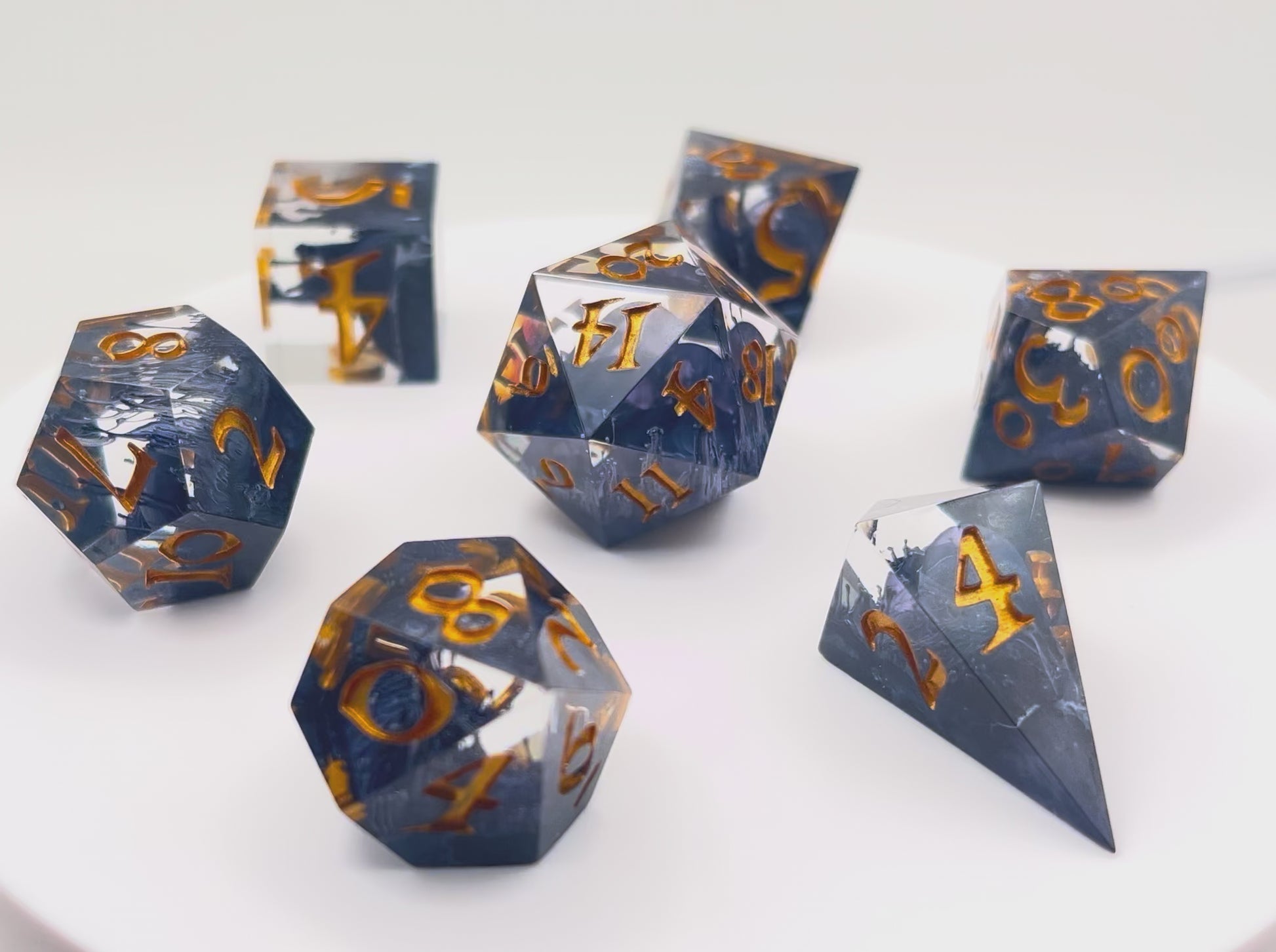 Video showing TTRPG D&D clear with black Petri effect resin dice set inked in gold