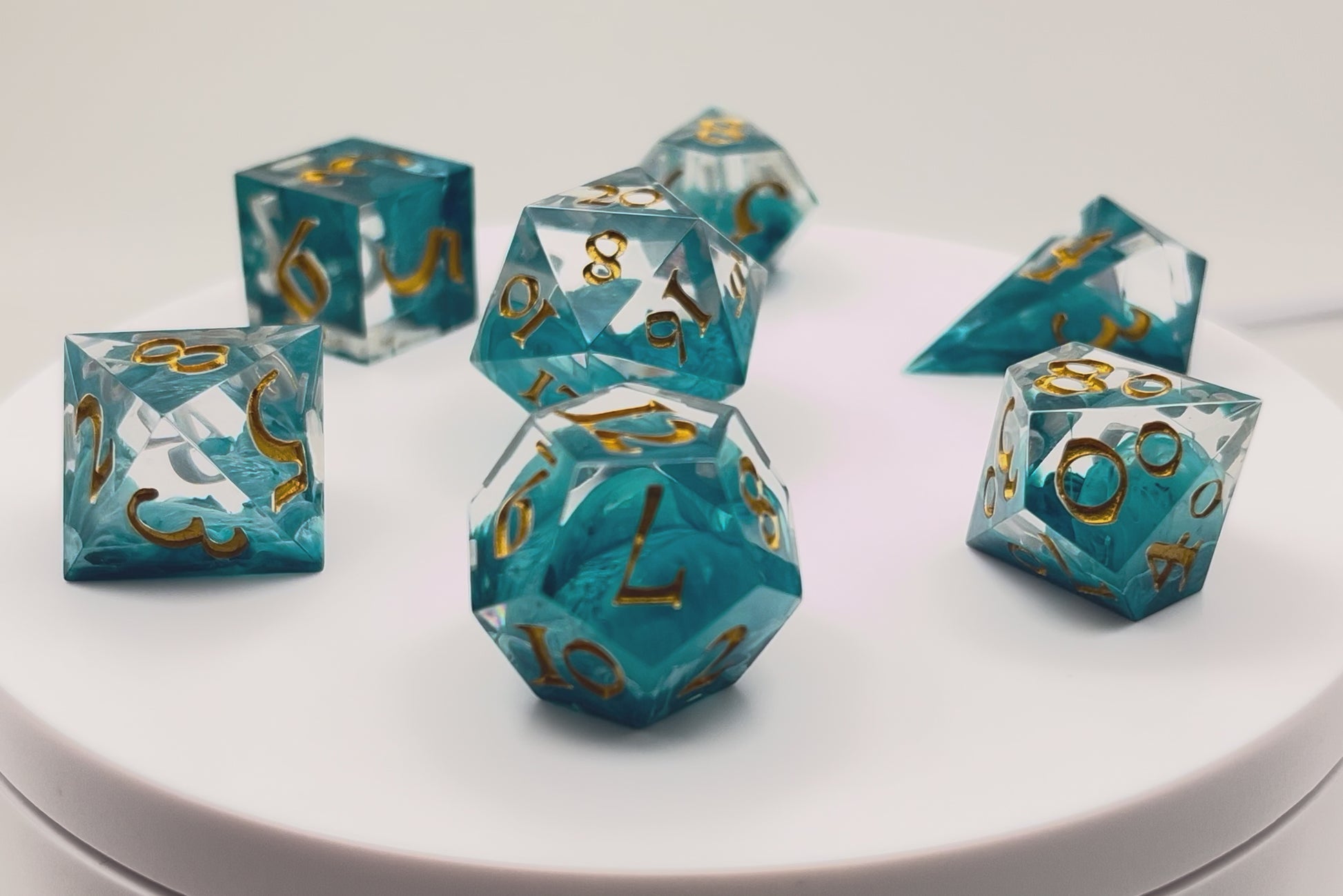 Video of Full set of TTRPG resin dice, petri-pour in white and Smurf blue, inked in Gold