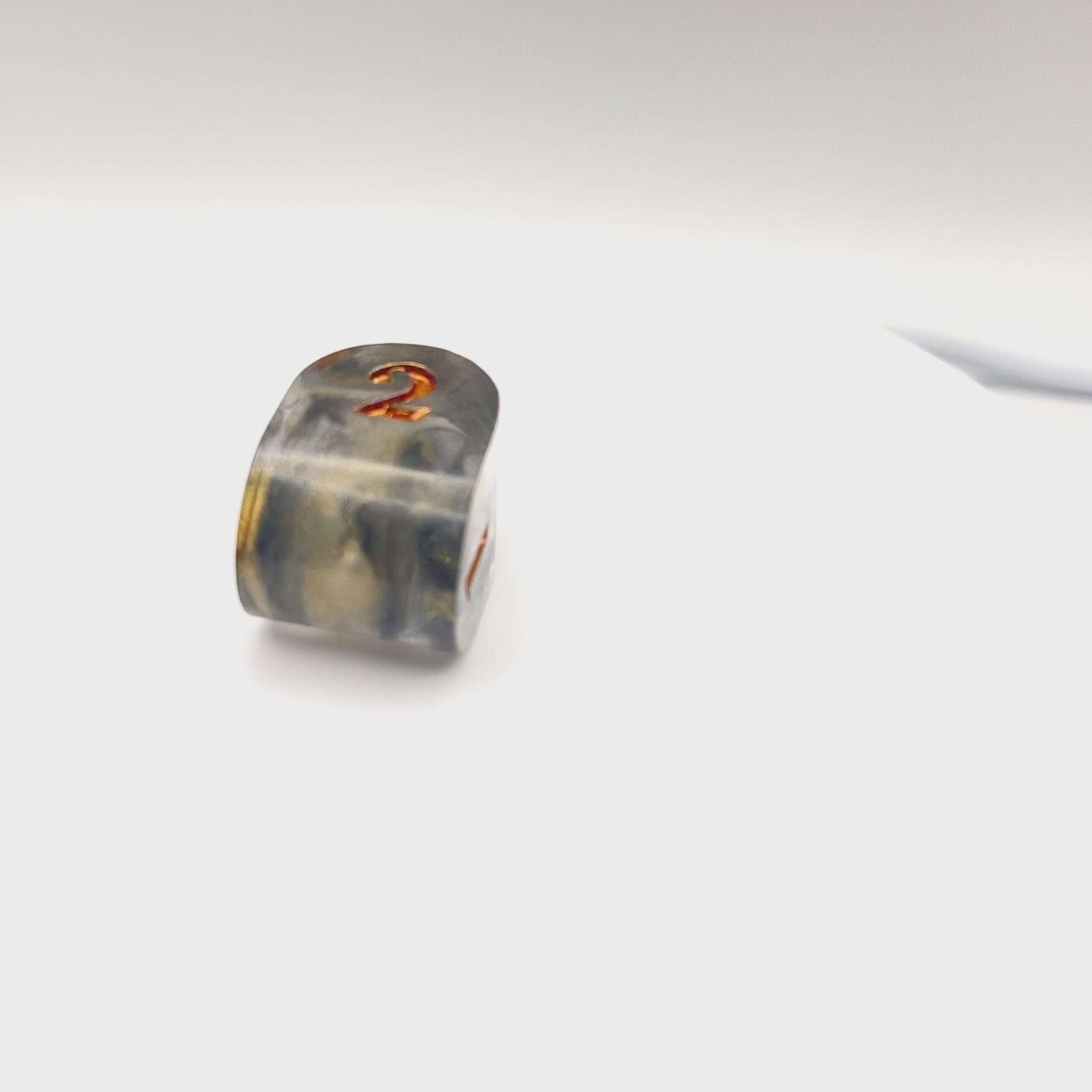 Video showing Resin infinity-shaped D4, semi-transparent using black and gold swirled dyes and inked in gold