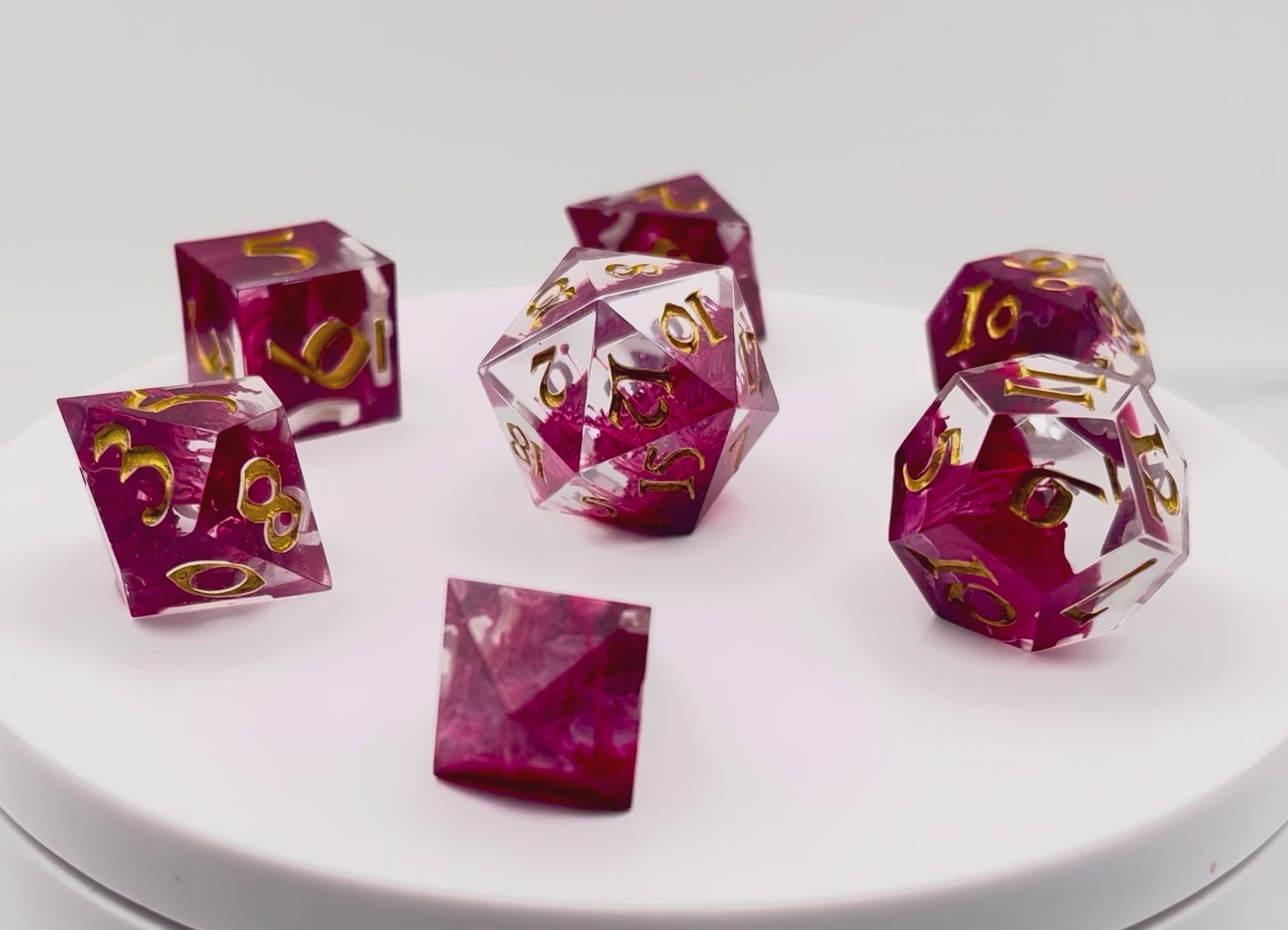 Video of Full set of TTRPG resin dice, petri-pour in white and Sweet Cherry, inked in Gold